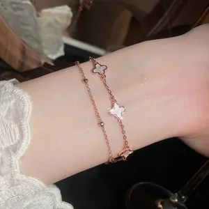 Primer plano detallado de pulsera de doble capa en oro rosa con tréboles blancos