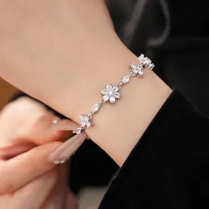 Elegant close-up of a vintage silver bracelet with zircon flower and cross charms