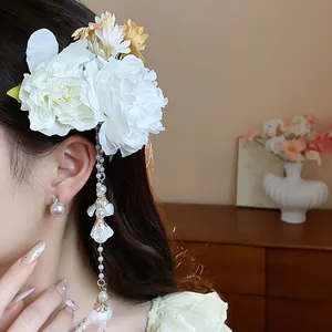 Detail view of an elegant floral hair clip with pearl tassels on a female model