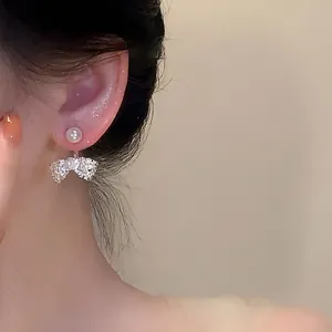 Elegant close-up view of French style bow pearl earrings on a person's ear detail