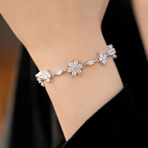 Elegant silver-toned bracelet with sparkling floral and cross cubic zirconia on wrist.