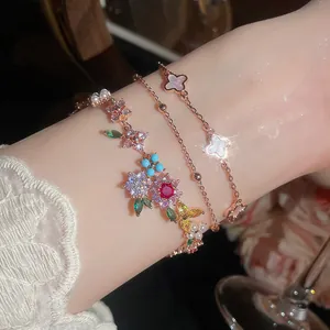 Primer plano de elegantes pulseras bañadas en oro de 18k con flores de circonita y perlas
