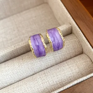 Dettaglio orecchini a C in smalto viola con bordi dorati martellati in scatola