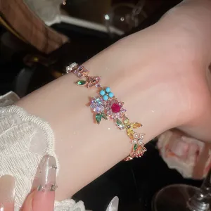 Primer plano de una pulsera floral bañada en oro de 18k con circonitas de colores
