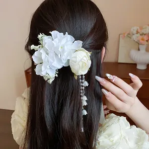 Detail of white fabric flowers and dangling pearl fringe hair clip on brunette hair