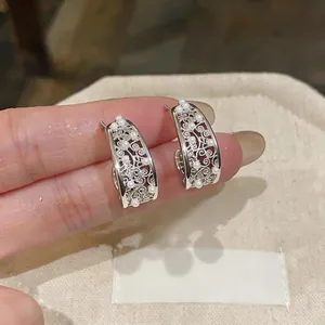 Close-up of silver-tone hollow floral C-shape earrings with delicate white pearl accents
