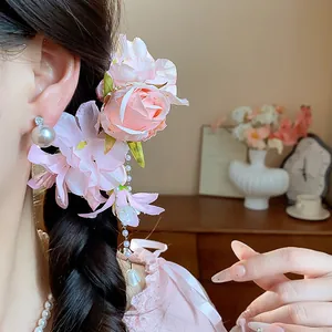 Detail shot of a sweet pink floral hair clip with pearl tassels on a braided hairstyle