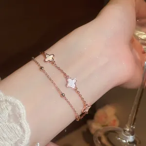 Detalle de una elegante pulsera de dos capas en oro rosa con tréboles en la muñeca