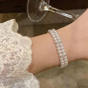Close-up of double-layer pearl bracelet with 18K gold plated accents on wrist.