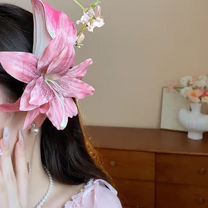 Close-up of a pink fabric lily flower hair clip with pearl detail on a model's hair.