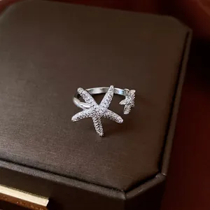 Elegant silver starfish open ring with sparkling cubic zircons on dark jewelry box