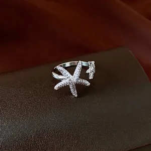 Sparkling zircon starfish open ring in silver finish displayed on textured dark leather.