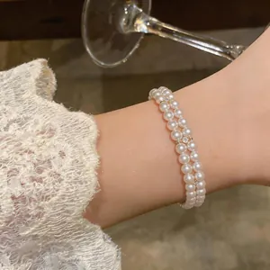 Detail view of elegant double-layered pearl bracelet with gold accents on a wrist.