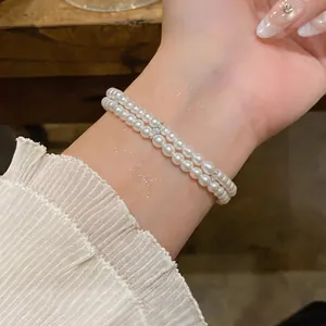 Close-up detail showing the elegant double layer pearl bracelet and skin texture