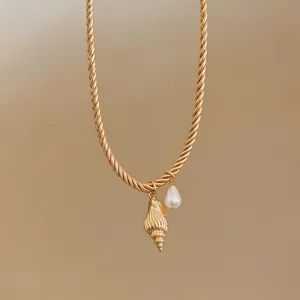 Detailed view of a gold rope chain necklace featuring seashell and pearl charms
