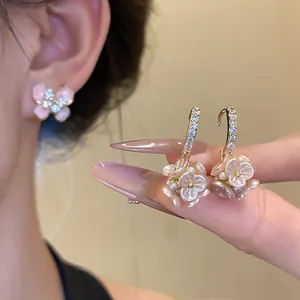Detail view of pink flower cluster earrings with pearls and butterfly stud earring