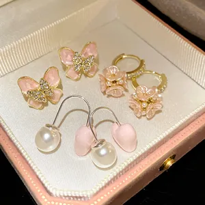 Detailed view of pink butterfly, flower, and heart pearl earrings in a box