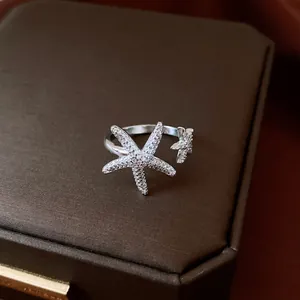 Detailed view of silver-tone starfish open ring with sparkling cubic zirconia on a brown box