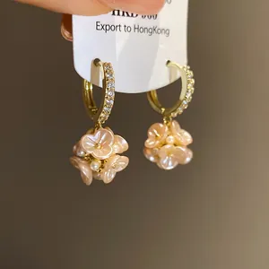 Elegant gold hoop earrings featuring delicate pink flowers and small pearls in a macro detail shot
