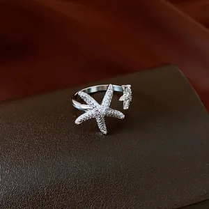 Detailed view of a silver starfish open ring with sparkling zircon stones on leather.