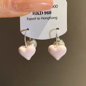 Close-up detail of vintage pink enamel heart earrings with pearl back closures