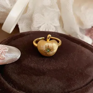 Vue détaillée d'une bague en forme de pomme dorée avec zircon vert et fini brossé