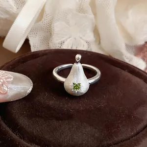 Gros plan d'une bague en argent brossé en forme de poire avec une pierre zircon verte