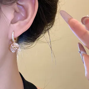 Close-up view of delicate pink flower cluster drop earrings with pearl accents and gold hoops
