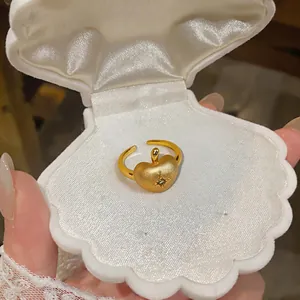 Gros plan d'une bague pomme en or brossé avec zircon étoile dans un écrin à bijoux.