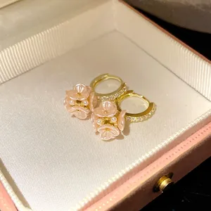 Close-up view of elegant pink flower and pearl hoop earrings resting in a gift box