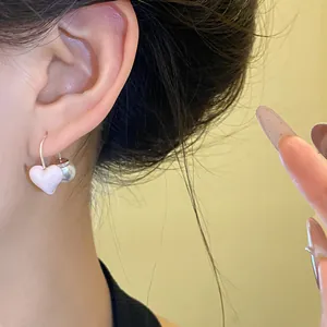 Macro view showing the pink heart drop and pearl detail on a stylish silver earring