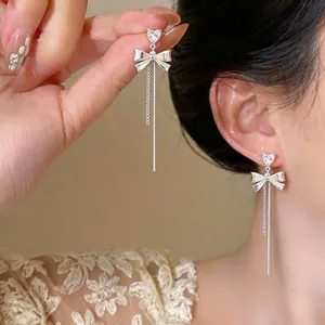 Detailed view of silver bow tassel earrings featuring sparkling heart-shaped zircons