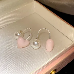 Close-up of elegant pink heart and white pearl drop earrings in a vintage jewelry box