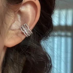 Gros plan d'un ear cuff vintage en dentelle avec des pierres de zircone sur l'oreille.
