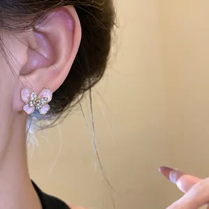 Detailed view of a vintage pink butterfly enamel stud earring on a model's ear.