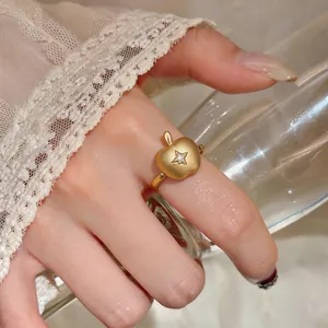 Vue macro détaillée d'une bague pomme en or brossé avec une étoile en zircone incrustée.