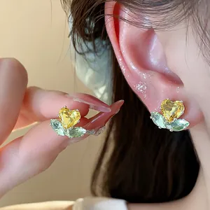 Detailed view of elegant flower stud earrings featuring yellow heart and green leaf zircons