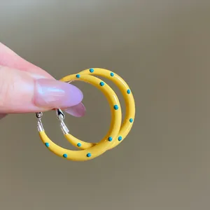 Primo piano di orecchini a cerchio gialli con motivi a pois blu