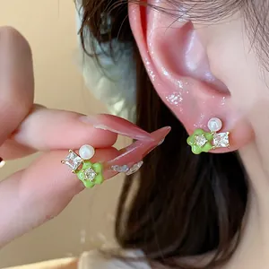 Detailed view of dainty green flower stud earrings with sparkling zircon and pearl accents