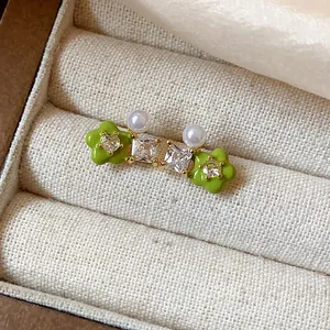 Close-up of green flower stud earrings with zirconia and pearls in a jewelry box