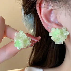 Detailed macro view of light green flower-shaped stud earrings with subtle shimmer