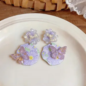 Primo piano di orecchini a fiore in resina lavanda con dettagli a farfalla