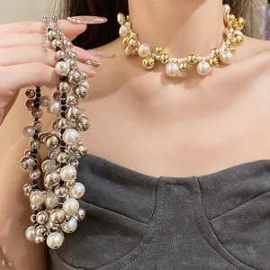 Vue détaillée d'un collier de perles épaisses et de billes dorées porté par un mannequin.