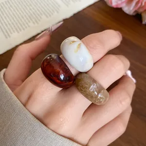 Détail de trois bagues rondes en résine à la mode en ambre, blanc et finition marbre