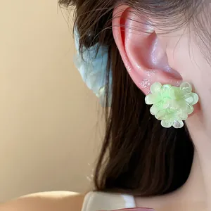 Close-up detail of the light green resin flower stud earring with layered petals