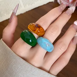 Gros plan détaillé d'un ensemble de trois bagues en résine ambre, verte et bleu marbré