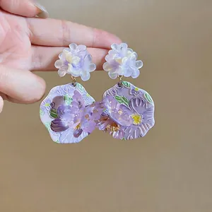 Dettaglio macro di orecchini a fiore in resina viola con eleganti motivi a farfalla