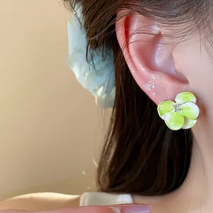 Close-up view of elegant green floral stud earring with sparkling zircon worn on model's ear