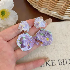 Dettaglio ravvicinato di orecchini a fiore in resina viola con accento a farfalla