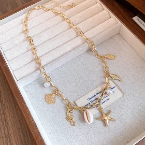 Detail view of a gold ocean-themed necklace with starfish, seashell, and pearl charms.